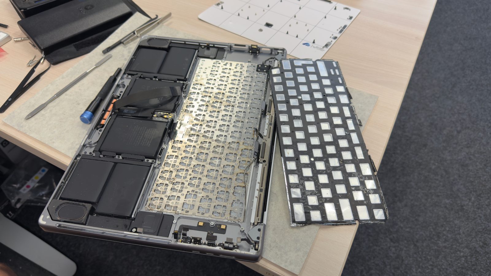 Rozebraný MacBook s vyjmutou klávesnicí na servisním stole